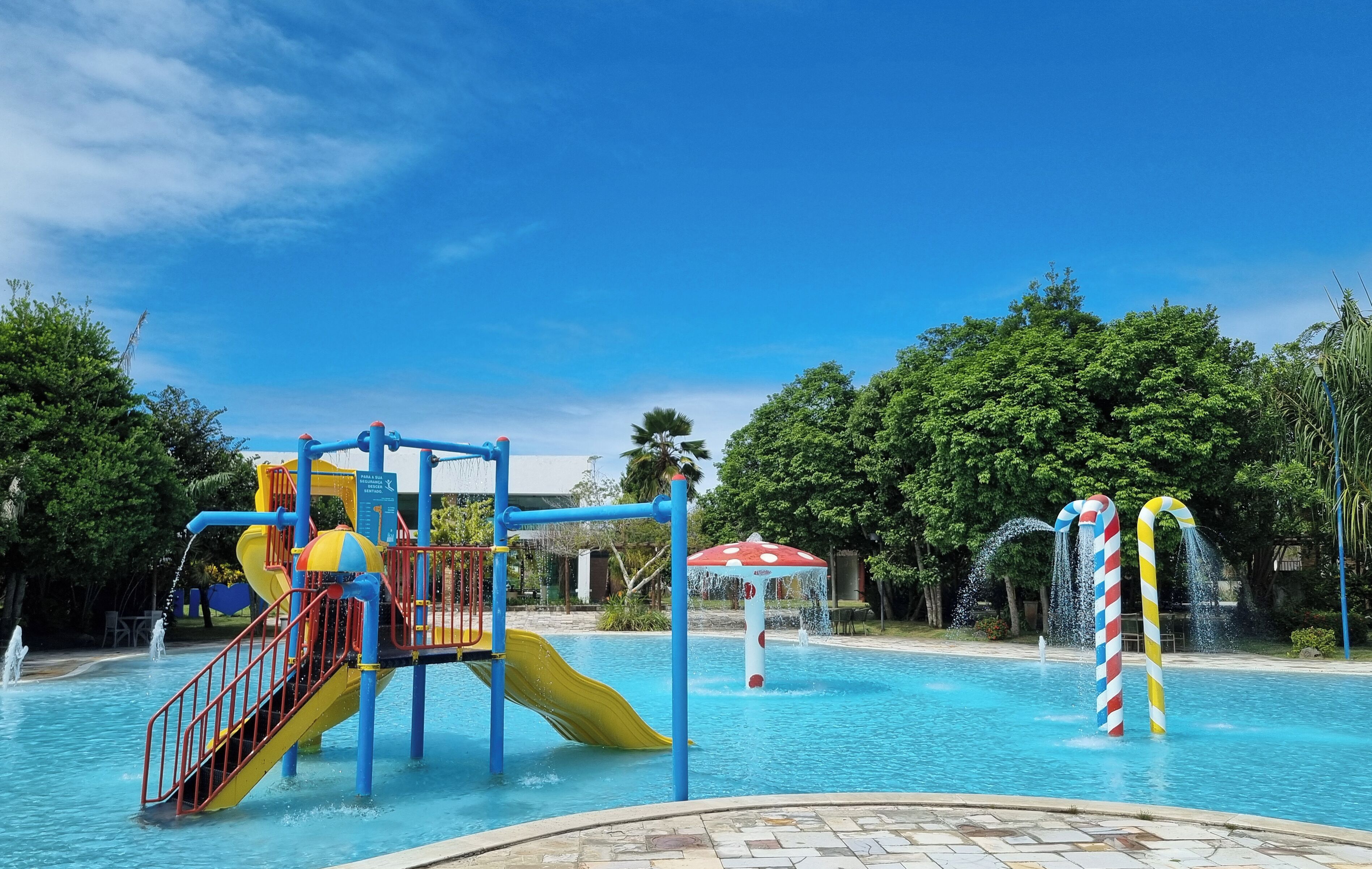 Un parque acuático con tobogán, estructuras de juego y una piscina.