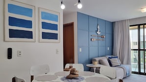 A dining area with a round table, chairs, and a wall with nautical-themed decor. - Suíte + Quarto com Ar, Wi-Fi e 2 Vagas (Barra de São Miguel)