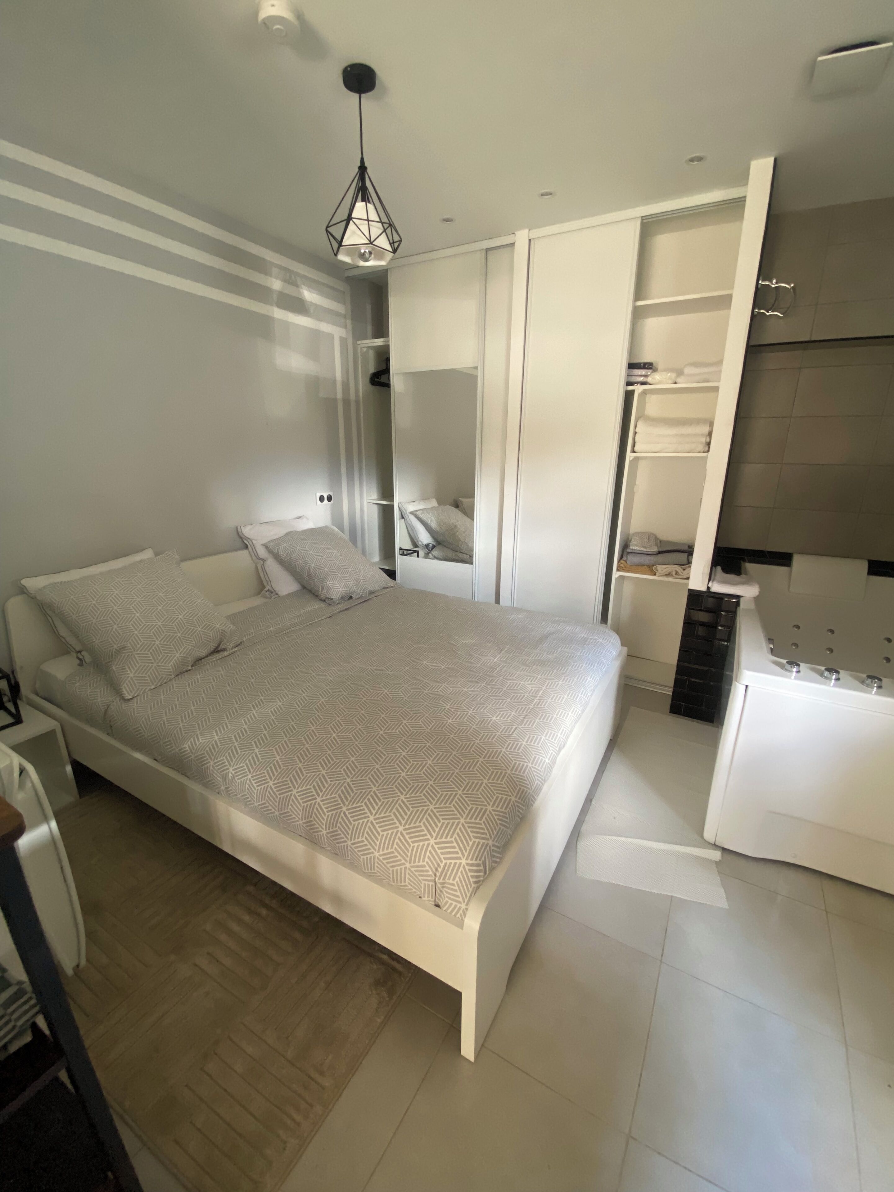 A modern bedroom with a bed, a wardrobe, and a bathroom.