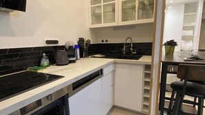 Moderni keittiö, jossa on valkoiset kaapit, musta työtaso ja sisäänrakennettu uuni.