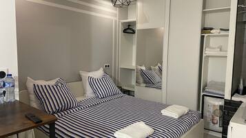 Un dormitorio con cama, mesitas de noche, un armario y un espejo.