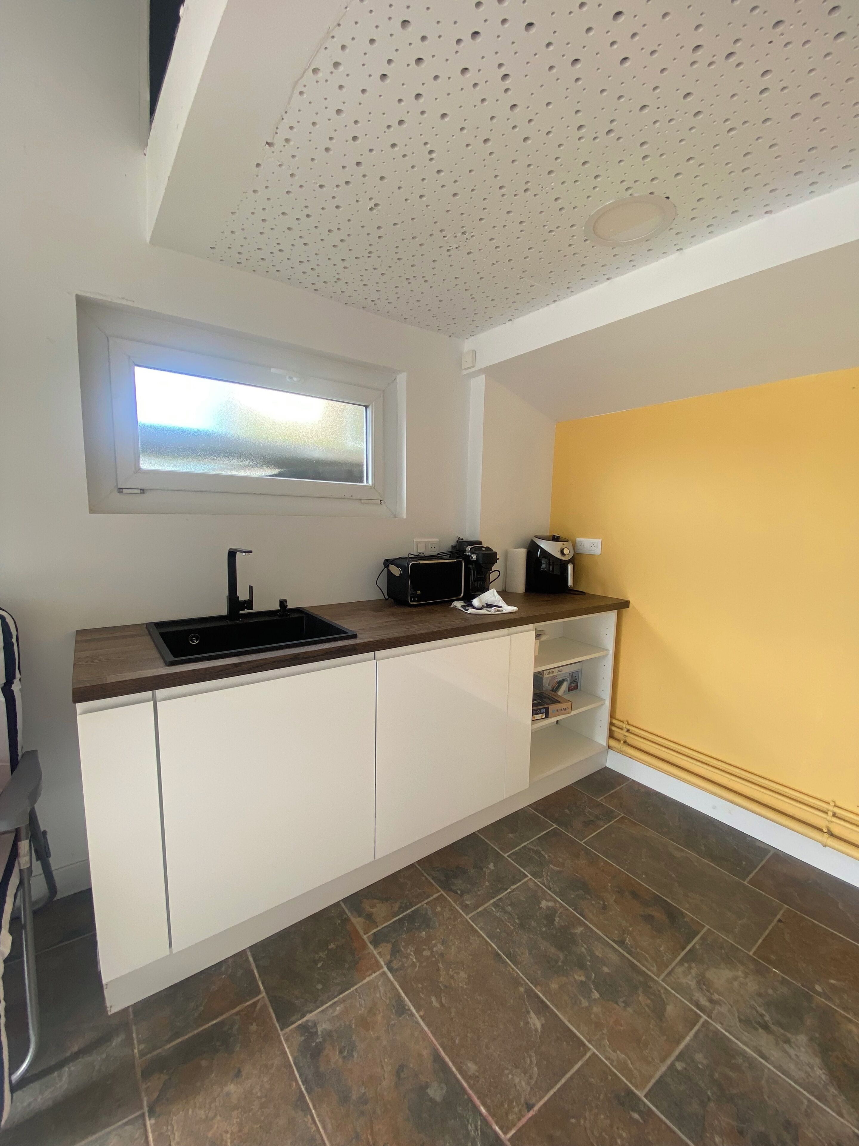 A kitchen with a window, a sink, a microwave, and cabinets.