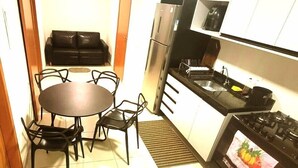 A compact kitchen with a dining table and chairs, a refrigerator, a stove, and a microwave. - Salt Beach Atalaia Residence Inn - P101 (Salinópolis)