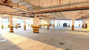 A multi-level parking garage with striped pillars and concrete floors. - Salt Beach Atalaia Residence Inn - P101 (Salinópolis)