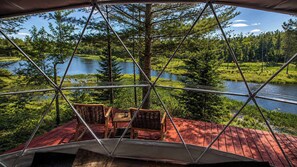 Una estructura de domo geodésico con vista a un lago y un bosque.