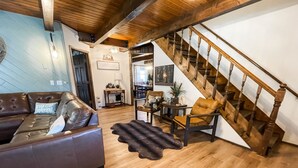 A cozy living room with a brown leather sofa, a wooden staircase, and a dining area with wooden furniture. - Perfect Family Cabin! 3 Master Suites, Sleeps 10, next to the park! (South Fork)