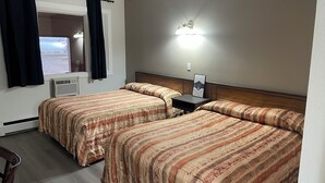 A hotel room with two beds, a window with curtains, a wall-mounted air conditioner, a nightstand with a framed menu, and a wall-mounted light fixture. - Niton Junction Motel (Niton Junction)