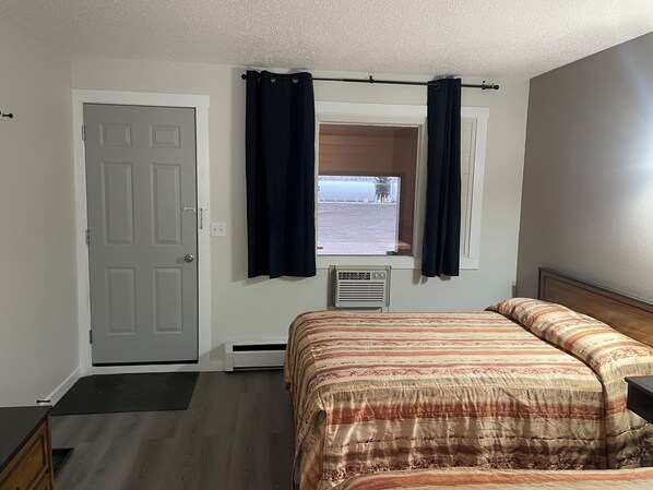 Un dormitorio con cama, ventana con cortinas, una puerta y un radiador.