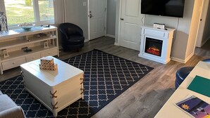 Una sala de estar con chimenea, televisor, estantería y ventana con vistas al exterior.