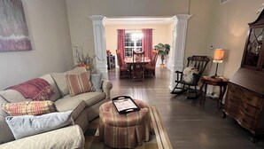 Un salon avec un canapé, un pouf et, au fond, un coin repas.