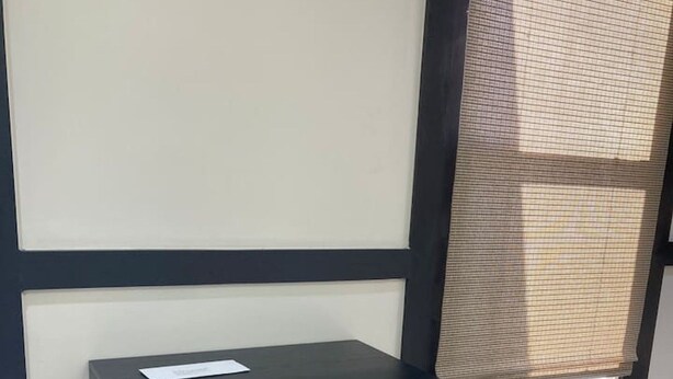Un classeur noir, doté de tiroirs, est placé contre un mur près d’une fenêtre.