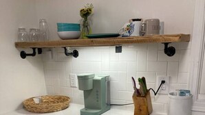 Une cuisine équipée d’un lave-linge, d’une machine à café et d’une étagère contenant divers objets.