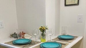 A dining area with a white table, blue plates, yellow stools, and a vase with yellow flowers. - Chic luxury studio, Downtown Danville, Pets OK, Centre College & Bourbon Trail  (Danville)