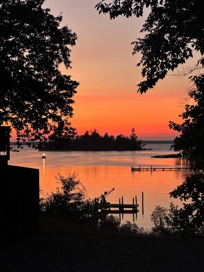 A sunset view over a calm body of water with a dock and trees framing the scene. - Charming studio in lovely Topping with AC, WiFi that has stunning water views! (Topping)