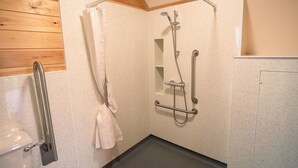 A shower area with a handheld showerhead, a grab bar, and a white towel hanging on a rack. - Rural Cabin With Hot Tub & Accessible Facilities (Kinloss)