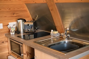 Une cuisine compacte équipée d’un four à micro-ondes, d’un grille-pain, d’une bouilloire et d’un évier.