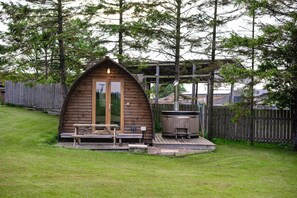 Une cabane en bois avec une véranda, un jacuzzi et une terrasse en bois.