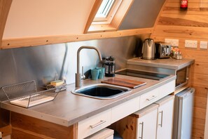 A modern kitchen with a skylight, stainless steel appliances, and wooden cabinetry. - Cosy Rural Cabin With Accessible Facilities (Kinloss)