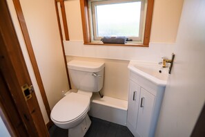 A small, compact bathroom with a toilet, sink, and window. - Rustic Log Cabin With Hot Tub (Kinloss)
