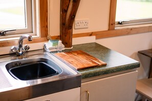A kitchen with a stainless steel sink, wooden cutting board, and a green countertop. - Rustic Log Cabin With Hot Tub (Kinloss)