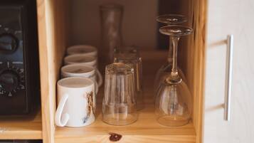 A wooden cabinet with various glassware and ceramic mugs.