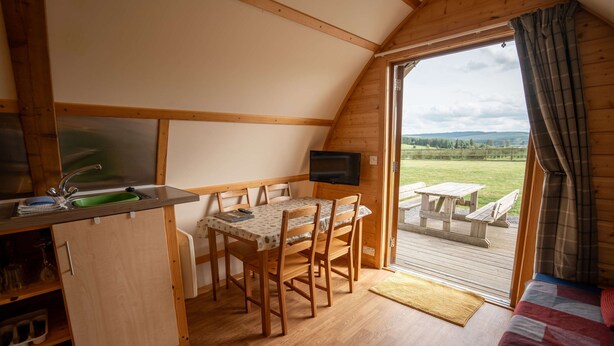 A cozy cabin with a dining area, a TV, and a view of the outdoors.