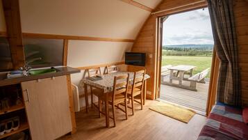 A cozy cabin with a dining area, a TV, and a view of the outdoors.