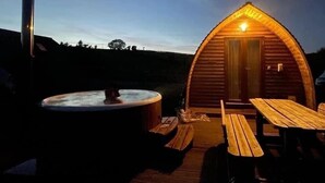 A wooden cabin with a hot tub and picnic tables on a wooden deck. - Cosy Cabin with Hot Tub in the Welsh Countryside (Llanbrynmair)