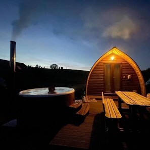 A wooden cabin with a hot tub and picnic tables on a wooden deck. - Cosy Cabin with Hot Tub in the Welsh Countryside (Llanbrynmair)