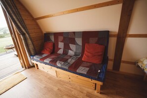 A wooden bench with a quilted backrest and cushions, positioned in a room with wooden beams and a wooden floor. - Cosy Cabin with Hot Tub in the Welsh Countryside (Llanbrynmair)