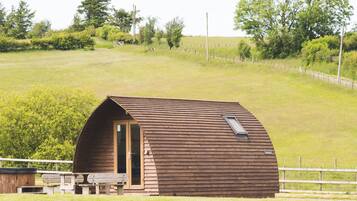 A wooden cabin with a sloped roof, a door, and a small porch area.