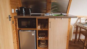 A compact kitchenette with a refrigerator, microwave, and sink.