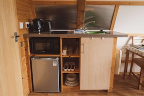 A compact kitchenette with a refrigerator, microwave, and sink. - Cosy Cabin with Hot Tub in the Welsh Countryside (Llanbrynmair)