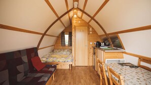 A cozy attic bedroom with a bed, a sofa, a small kitchenette, and a window. - Rural Cabin in the Welsh Countryside (Llanbrynmair)