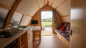 A cozy, wooden interior with a kitchen, dining area, and a sofa. - Rural Cabin in the Welsh Countryside (Llanbrynmair)
