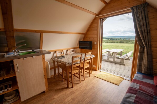 A cozy cabin with a dining area, a TV, and a view of the outdoors.