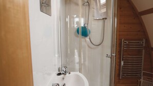 A modern bathroom with a glass-enclosed shower, a white sink, and wooden beams on the ceiling. - Rural Cabin in the Welsh Countryside (Llanbrynmair)