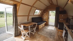 A cozy, semi-open cabin with a wooden interior, a dining area, and a kitchen. - Wooden Cosy Cabin with Hot Tub in Mid Wales (Llanbrynmair)