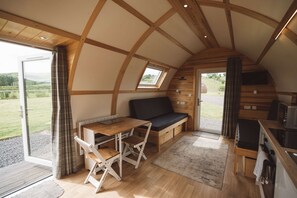 Un chalet accueillant, partiellement ouvert, avec un intérieur en bois, un coin repas et une cuisine.