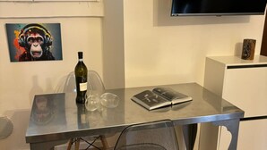 Moderni huone, jossa on lasipöytä, tuoli, viinipullo ja seinälle asennettu televisio.