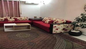 A living room with a red sofa set, a white coffee table, and a patterned rug. -  5-beds apartment with AC, WiFi, Smart TV # Meknes (Meknes)