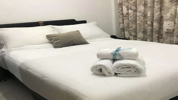 A neatly made bed with white linens and a folded towel on the side. -  5-beds apartment with AC, WiFi, Smart TV # Meknes (Meknes)