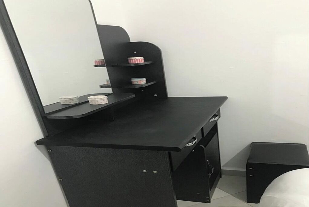 A black desk with a mirror, shelves, and storage compartments.