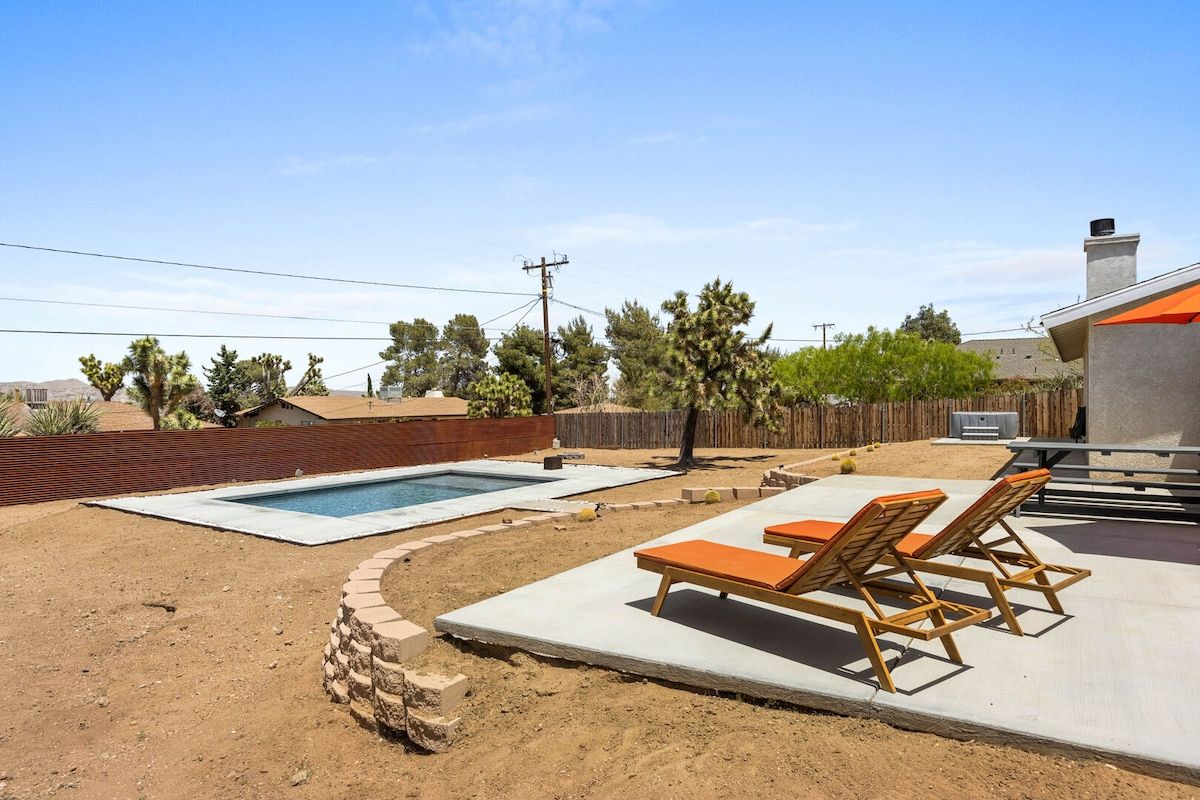 A backyard with a swimming pool, lounge chairs, and a barbecue area.