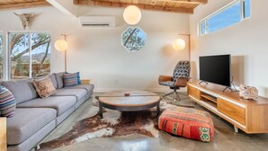 A modern living room with a sofa, a round coffee table, a television, and a wooden entertainment unit.