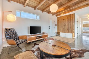 Una sala de estar moderna con televisor de pantalla plana, sillón de cuero, mesa de centro de madera y alfombra de piel de vaca.