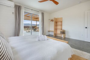 A bedroom with a large bed, a wooden wardrobe, and a view through a sliding door to an outdoor area. - Desert Hearts Ranch - Private Oasis with Dark Skies! (Joshua Tree)
