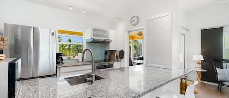A modern kitchen with stainless steel appliances, a granite countertop, and a view of the outdoors.