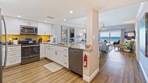 A modern kitchen with stainless steel appliances, a dishwasher, and a granite countertop. - Reef Club 209 - Oceanview Retreat w/ Pool, Tennis & Sunset Balcony (Indian Rocks Beach)
