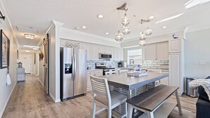 A modern kitchen with white cabinetry, stainless steel appliances, and pendant lighting.